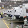Workers in highvis on the lefthand side inspect a line of pop-top caravans within a factory. Caravan Industry Victoria assess caravan manufacturers against five criteria in the RV Master Manufacturer programme