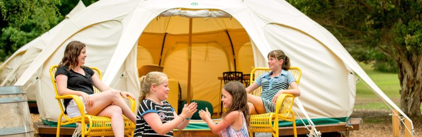 Kids sitting on timber steps leading to a yurt at one of 300 locations within the BIG4 Holiday Parks network, searchable on big4.com.au