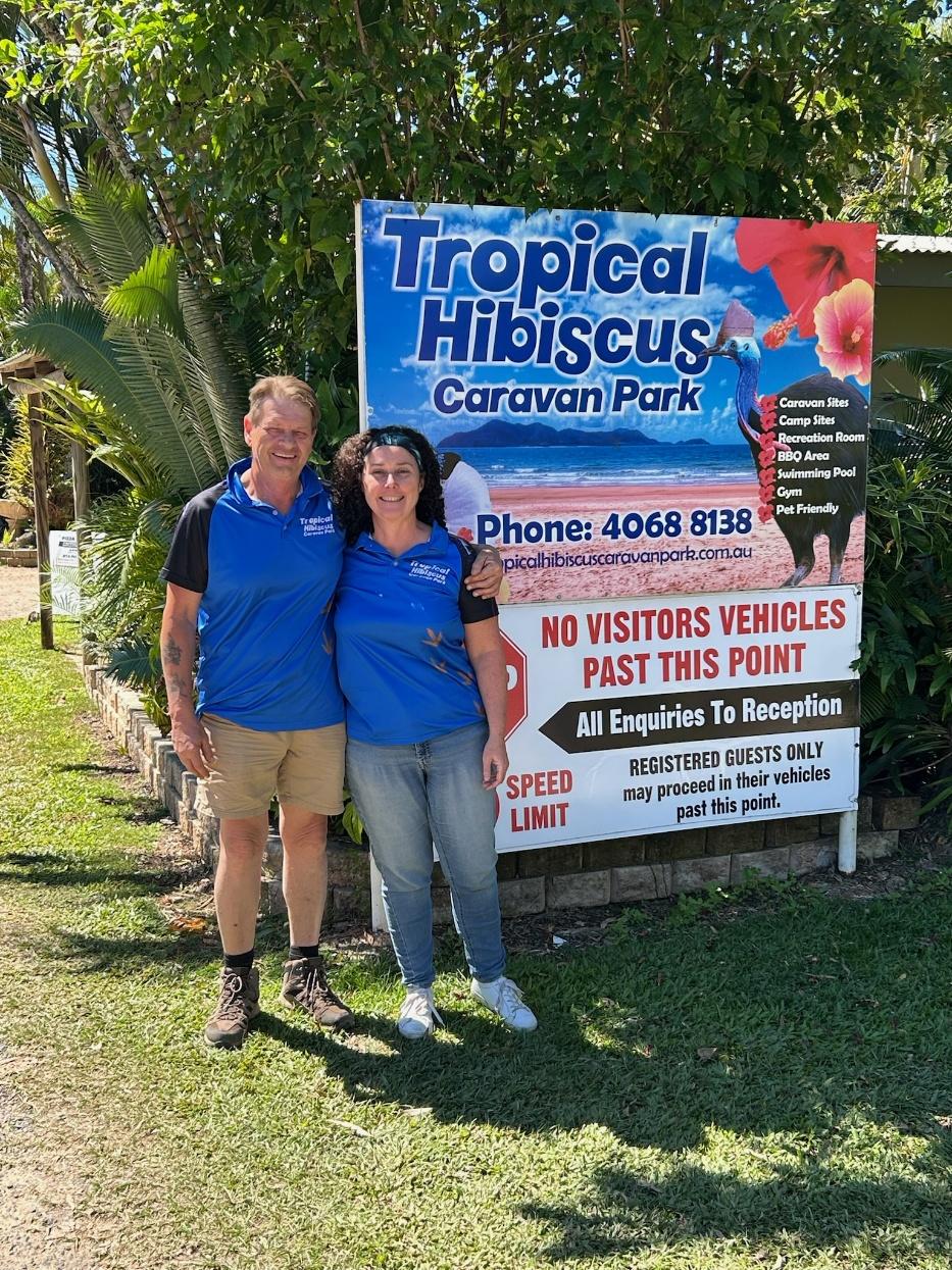 4x4xplor content creators keith and christine stand in front of the Tropical Hibiscus sign, the caravan park they now own and manage