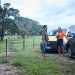 A man at the side of the road by his red fourbie looks happy to see an RACV technician standing in front of a yellow RACV mechanic van